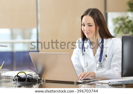 Concentrated doctor working on line with a laptop sitting in a desk in a consultation