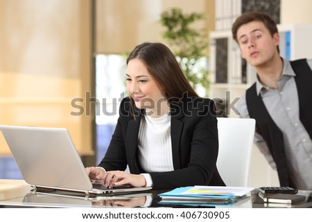 Businessman spying his colleague who is working at her desktop at job