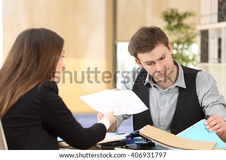 Incompetent businessman with disordered desktop attending an upset client giving her a dirty report at office
