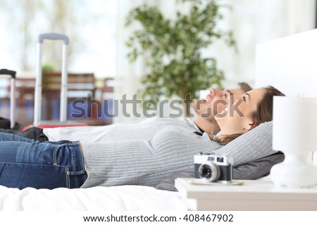 Couple of tourists relaxing lying on the bed in an hotel room on vacations