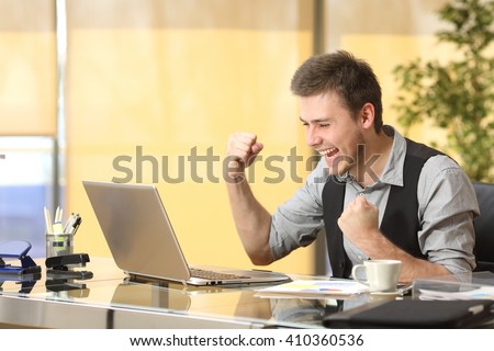 Excited successful businessman working on line with a laptop in a desktop at office