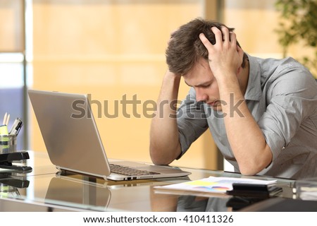 Worried businessman lamenting in front of a computer after a big mistake at office