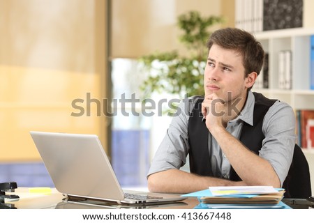 Serious doubtful businessman thinking and looking sideways sitting in a desk at office