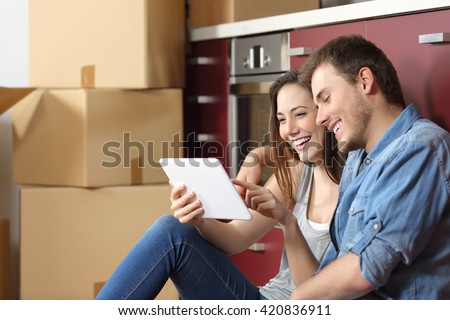Couple moving home and buying on line with a tablet sitting on the floor in the kitchen