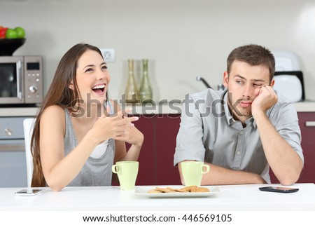 Bored husband hearing his wife talking during breakfast in the kitchen at home