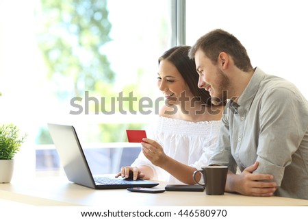 Couple of buyers buying on line with credit card and a laptop at home or hotel