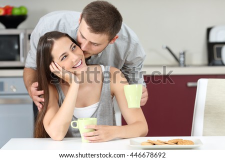 Happy husband kissing on cheek her wife at breakfast. Marriage life concept