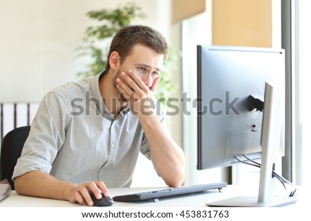 Worried businessman working trying to solve troubles on line with a desktop computer at office