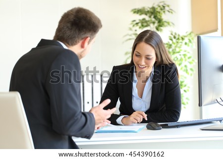 Salesclerk talking trying to convince to a happy client in a desktop at office