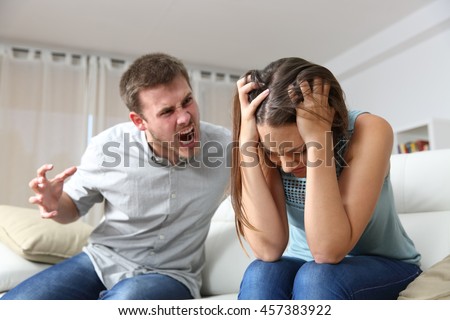 Couple arguing. Husband shouting to a scared wife in a house interior