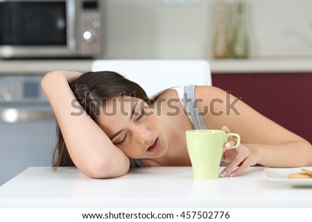 Tired girl sleeping on the table of the kitchen at breakfast