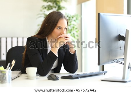 Concentrated businesswoman trying to solve a difficult assignment on line in a desktop computer at office