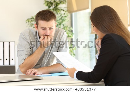 Nervous man looking how the interviewer is reading his resume during a job interview