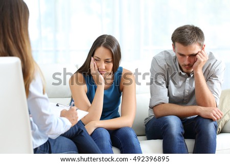 Sad couple listening to a marriage counselor during a therapy sitting on a sofa at home