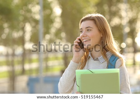 Happy student girl walking and calling on mobile phone  outdoors with a green background