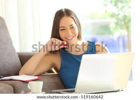 Happy entrepreneur working with a laptop on line sitting on the floor of the living room at home with a window in the background and a warm light
