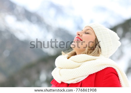 Happy woman breathing deep fresh air in winter on holidays in a snowy mountain