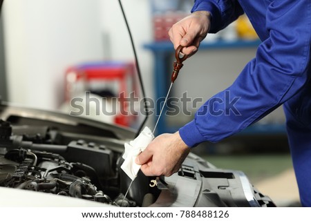 Close up of a car mechanic checking oil level in a mechanical workshop
