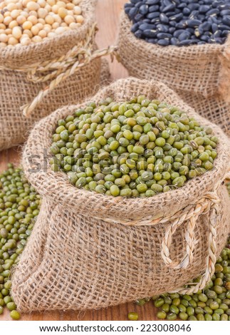 Raw Organic green Beans, Fresh Organic chicpea of Green mung beans in open Bags small burlap sack on wooden Table,