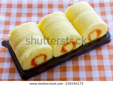 cake roll, swiss roll, Slices of sweet cream roll, Orange roll cake on black pack plate with tartan table cloth