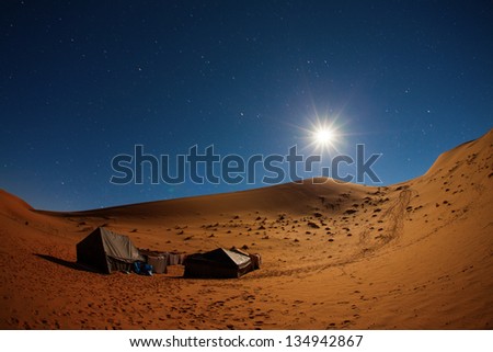 Camp in Sahara Desert in night with moon as star and moving stars