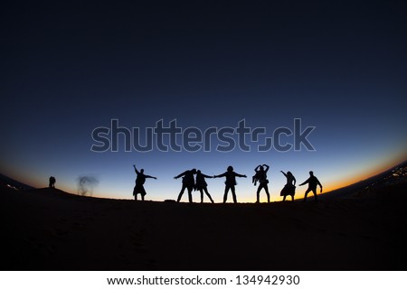 Group of happy people on top of a mountain in the Sahara desert, Morocco