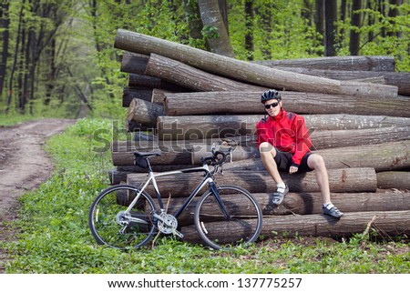 Mountain biker resting on wood in green forest