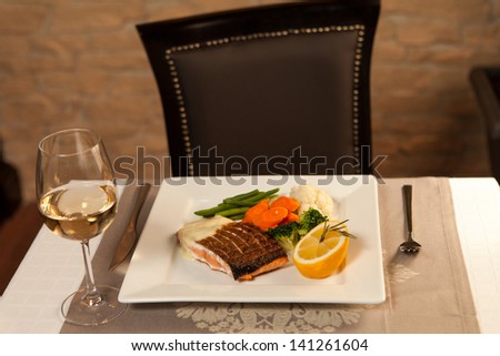 Grilled fish with vegetables, lemon and white wine on table