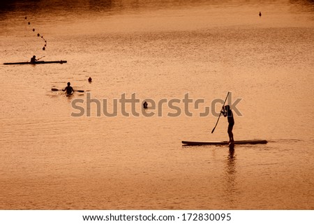 Silhouette of man paddleboarding at sunset, Florence river, Italy, recreation sport paddling ocean beach surf