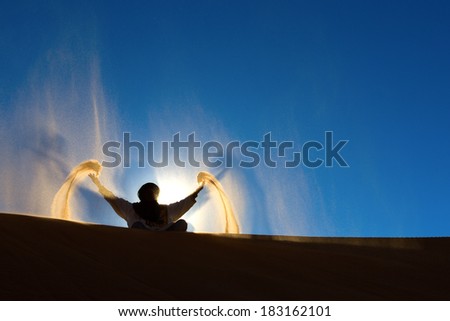 Berber playing and throwing with sands in Desert Sahara, creating angel with sands, Morocco