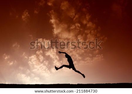 Silhouette of sport man jumping with blue sky and clouds on background