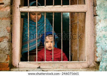 VARANASI, INDIA - JAN 19: Unidentified Indian boy with mother staying on a window of there house on January 19, 2015, Varanasi, India. Varanasi is one of the oldest city in the world.