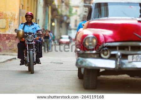 HAVANA - FEBRUARY 25: Unkown police man on bike and old classic car on February 25, 2015 in Havana. These vintage cars are an iconic sight of the island