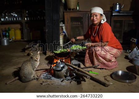 HIMALAYAN VILLAGE, NEPAL - NOVEMBER 24: Woman cooking inside of traditional house of Himalayan Village on November 24, 2014 in HIMALAYAN VILLAGE, Nepal