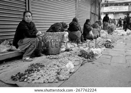 DURBAR SQUARE, KATHMANDU, NEPAL - NOVEMBER 28, 2014: Woman selling flower garlands for prayer at street market in Kathmandu, Nepal