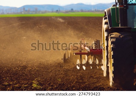 Tractor in sunset plowing the field