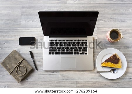 Unique Perspectives of a business table with an agenda, laptop, smart phone, coffee and dessert