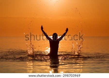 Man Splashing Water with his hands on a sea in a sunrise