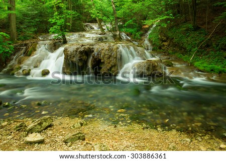 Cascade falls over mossy rocks in forest