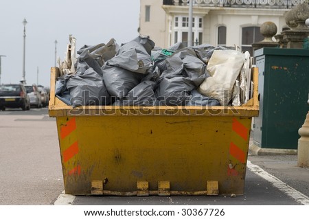 a skip full of refuse/trash sacks outside on the street