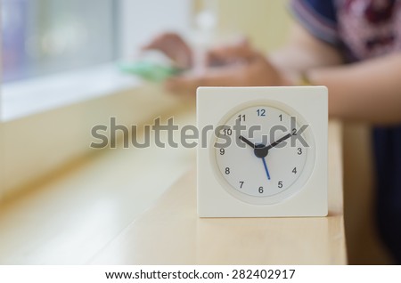The clock displays the time ten o\'clock ten minutes on mini bar side of the window  At coffee shop in  Bangkok  with blurred background image women are used  smart phone ,