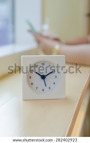 The clock displays the time ten o\'clock ten minutes on mini bar side of the window  At coffee shop in  Bangkok  with blurred background image women are used  smart phone ,