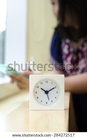 The clock displays the time ten o\'clock ten minutes on mini bar side of the window At coffee shop in Bangkok with blurred background  women are used smart phone