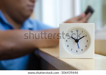 The clock displays the time ten o\'clock ten minutes on mini bar side of the window At coffee shop in Bangkok with blurred background men  used smart phone