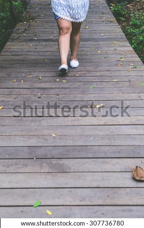 women walk alone  with  white shoes on wooden way in filter