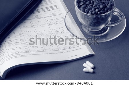 Toned business still life with report, cardholder, cup of coffee beans and pills
