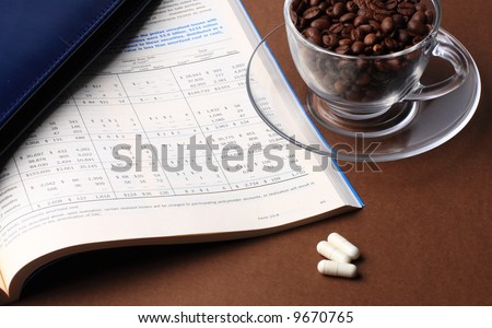 Business still life with report, cardholder, cup of coffee beans and pills