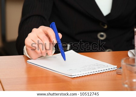 Woman\'s hand with pen and notepad on the table