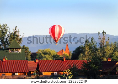 Flight of the hot air balloon above the village in Zakarpattya in the light of evening sun