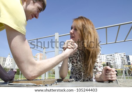The couple, young man and woman in the heat of the fight - who in the family of the chief. Armwrestling - fight on their hands.